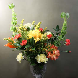 Mixed bouquet in a clear glass vase with yellow, orange, red, and white flowers