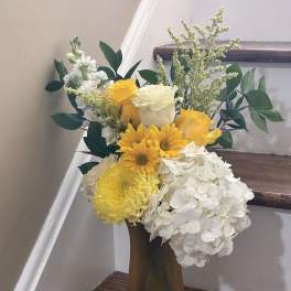 Yellow and white roses with white hydrangeas in a tall vase