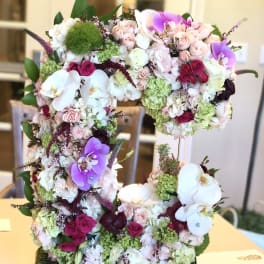 Large floral arrangement shaped like the number 5 with pink, white, and purple blooms