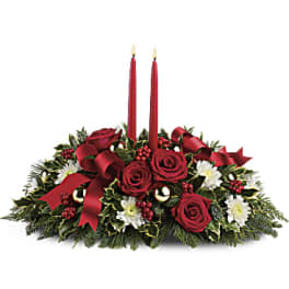 Red rose centerpiece with two red taper candles and holiday greenery