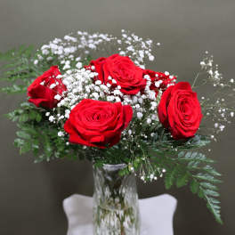 Red roses with white baby's breath in a clear glass vase