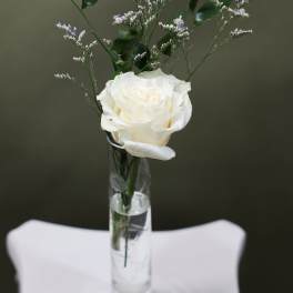White rose in a clear glass vase with airy purple filler