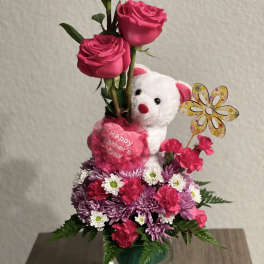 Pink rose arrangement with a teddy bear and flowers in a glass vase
