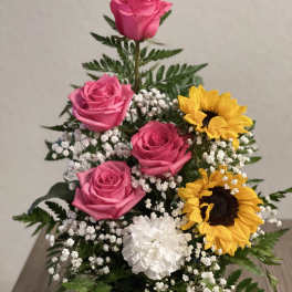 Pink roses and sunflowers arranged with white filler flowers