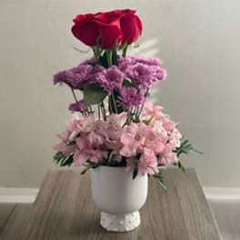Pink and purple floral arrangement in a white vase