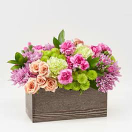Mixed pink and peach flowers in a rectangular wooden box