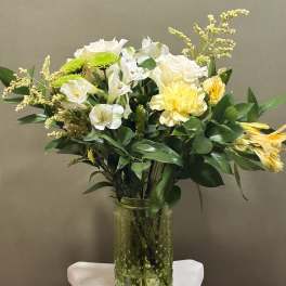White and yellow flowers arranged in a clear glass vase
