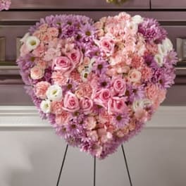 Heart-shaped floral arrangement of pink and white flowers on an easel