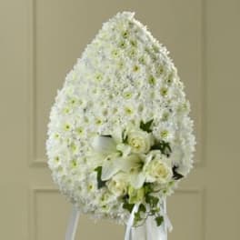 White funeral spray with roses and lilies on a stand