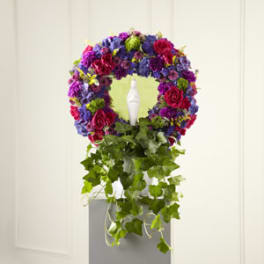 Circular floral wreath with purple, pink, and green flowers on a pedestal