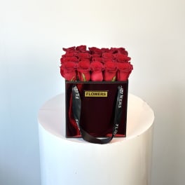 Box of red roses with black ribbon handles