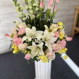 Pink tulips, white lilies, and roses in a tall white vase