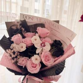 Pink and black rose bouquet with white accent flowers and decorative wrapping