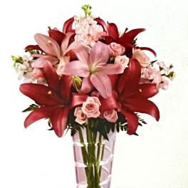 Pink and red floral bouquet in a tall pink glass vase