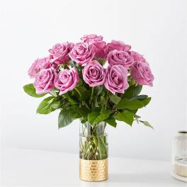 Pink roses arranged in a clear glass vase with a gold textured base