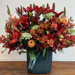 Large red and orange floral arrangement in a teal vase
