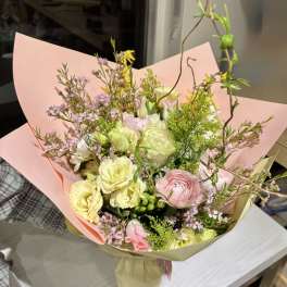 Pastel bouquet of pink, yellow, and white flowers wrapped in paper