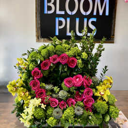 Large floral arrangement with pink roses, green blooms, and yellow orchids