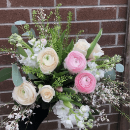 Hand-tied bouquet of pink and cream flowers with white accents.