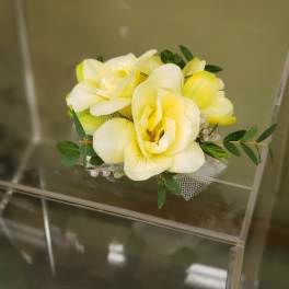 Small bouquet of pale yellow flowers with greenery and mesh wrap