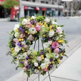 Large circular floral wreath on a black stand with pastel flowers