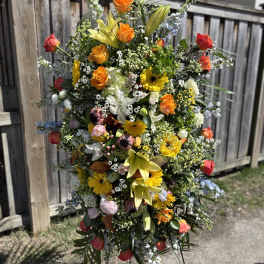 Tall standing floral spray with roses, lilies, and daisies in bright mixed colors