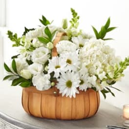 White flowers arranged in a wooden basket with green foliage