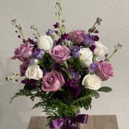 Pink and white roses with purple flowers in a glass vase