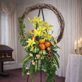 Standing floral spray with yellow lilies and orange roses on an easel
