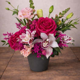 Pink roses and orchids arranged in a black pot