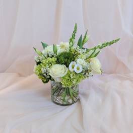 White and green floral arrangement in a clear glass vase