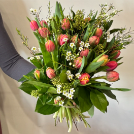 Bouquet of pink tulips with small white filler flowers and greenery