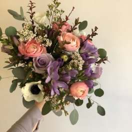 Handheld bouquet of pink, purple, and white flowers with eucalyptus