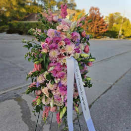 Standing sympathy spray of pink flowers with a white ribbon