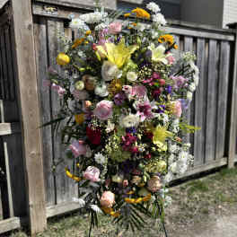 Large standing floral spray with mixed pink, white, yellow, and purple blooms