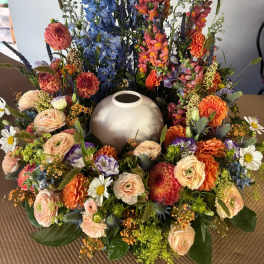Large floral wreath around a silver urn with blue and orange flowers