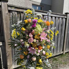 Large standing spray of mixed pink, yellow, orange, and white flowers