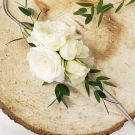 White rose bouquet with greenery on a rustic wood slice