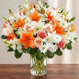Orange lilies and peach roses in a clear glass vase