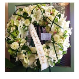 White floral wreath with a condolence ribbon