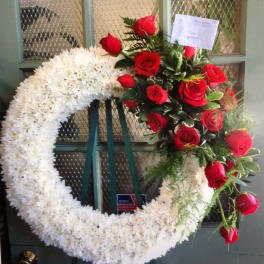 White floral wreath with red roses on a stand
