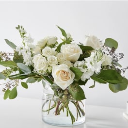 White roses and white blooms in a clear glass vase
