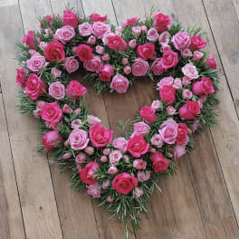 Heart-shaped rose arrangement in pink tones on a wooden floor