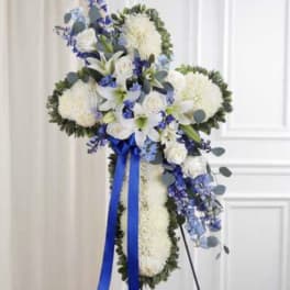 Standing floral cross with white and blue flowers and a blue ribbon