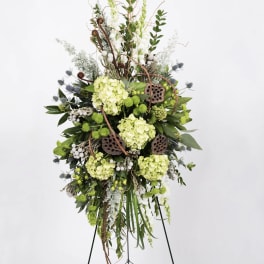 Tall floral standing spray with green hydrangeas and lotus pods