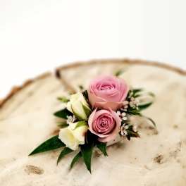 Small pink and white rose boutonniere on a cream hat