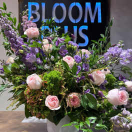 Large pink and purple floral arrangement in a white pedestal vase