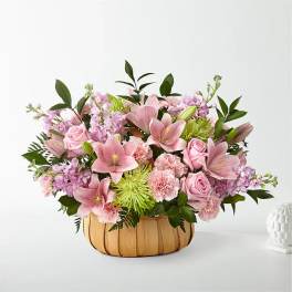 Pink lilies and roses in a woven basket arrangement