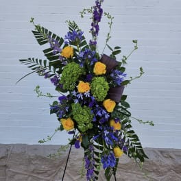 Tall floral spray with yellow roses, purple blooms, and green hydrangeas on a stand