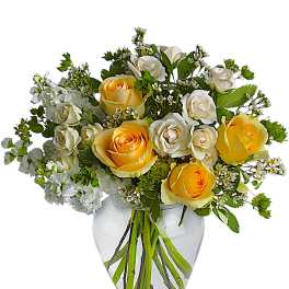 Yellow and white roses arranged in a clear glass vase